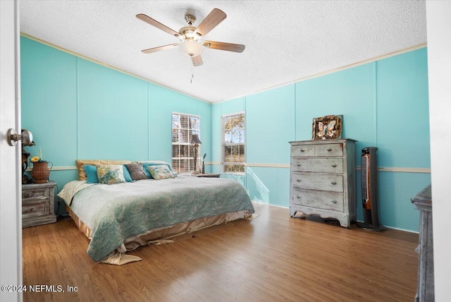 bedroom with hardwood / wood-style floors, a textured ceiling, vaulted ceiling, and ceiling fan