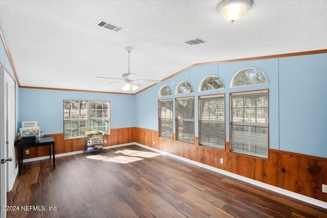 interior space with a textured ceiling, dark hardwood / wood-style flooring, crown molding, and vaulted ceiling