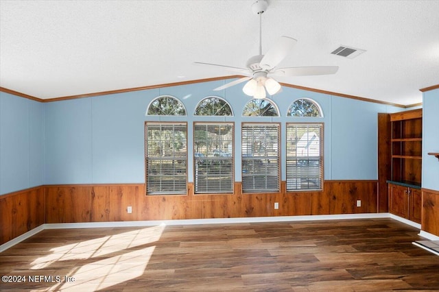 empty room with a textured ceiling, dark hardwood / wood-style floors, and ornamental molding