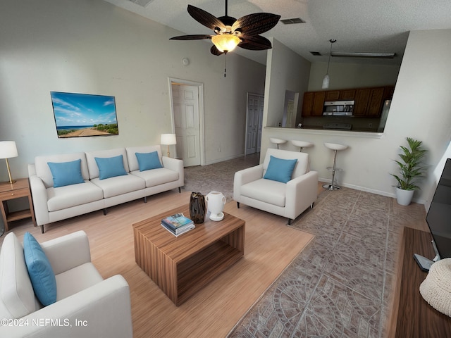 living room with ceiling fan, a textured ceiling, and high vaulted ceiling