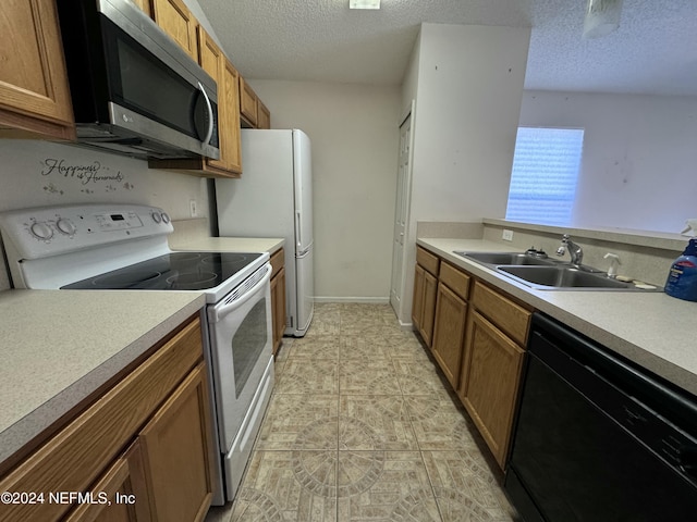 kitchen with a textured ceiling, light tile patterned flooring, white appliances, and sink