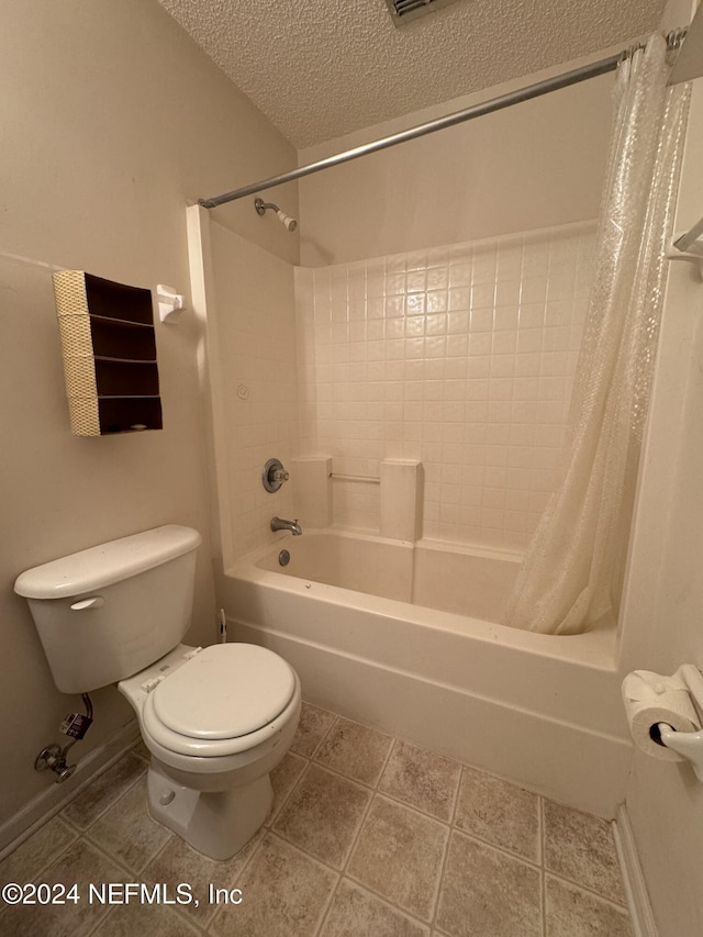 bathroom with tile patterned floors, toilet, a textured ceiling, and shower / tub combo