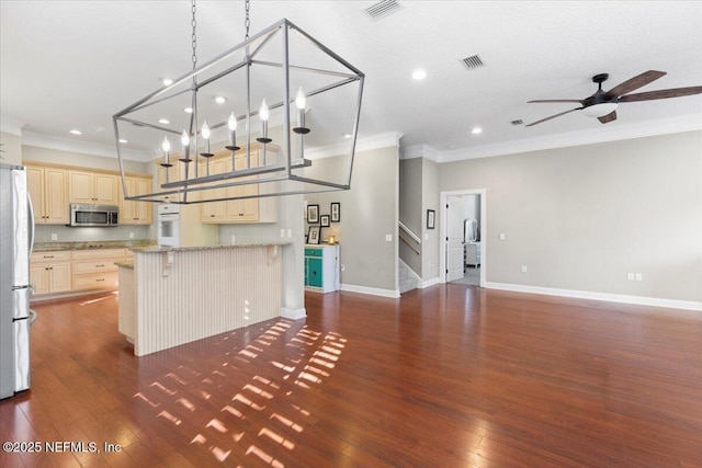 kitchen with oven, ceiling fan with notable chandelier, light stone countertops, ornamental molding, and a kitchen bar