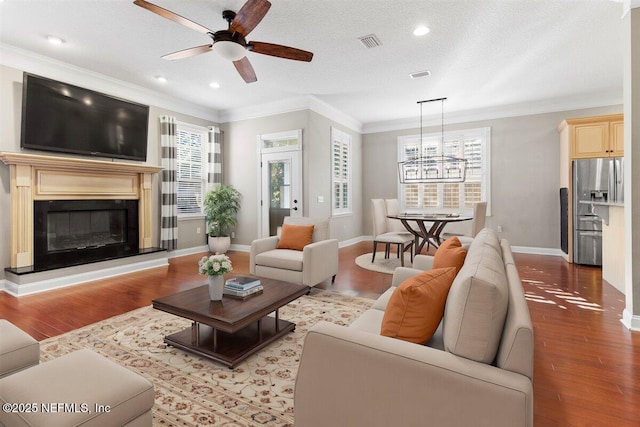 living room with ceiling fan, ornamental molding, a textured ceiling, and hardwood / wood-style flooring