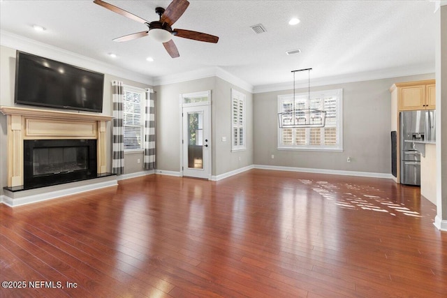 unfurnished living room with ceiling fan, dark hardwood / wood-style flooring, a textured ceiling, and ornamental molding