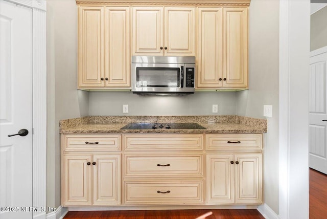 kitchen featuring cream cabinetry, black electric stovetop, and light stone countertops