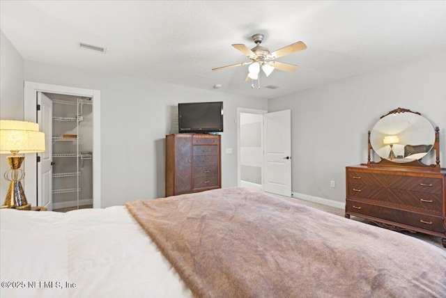 bedroom featuring carpet, a walk in closet, ceiling fan, a textured ceiling, and a closet