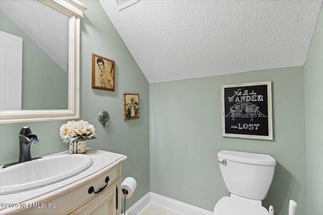 bathroom with a textured ceiling, vanity, lofted ceiling, and toilet