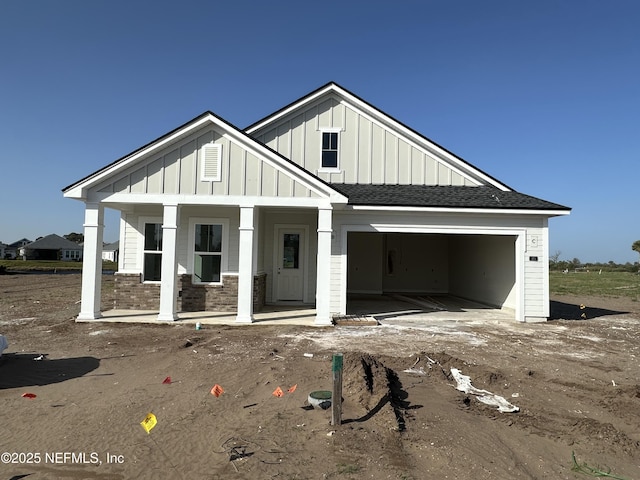 modern farmhouse with board and batten siding, a porch, a shingled roof, and a garage