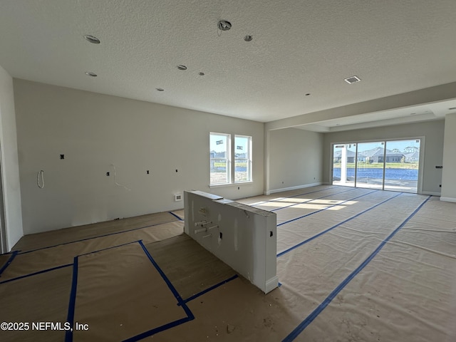 empty room featuring a textured ceiling, visible vents, and a wealth of natural light