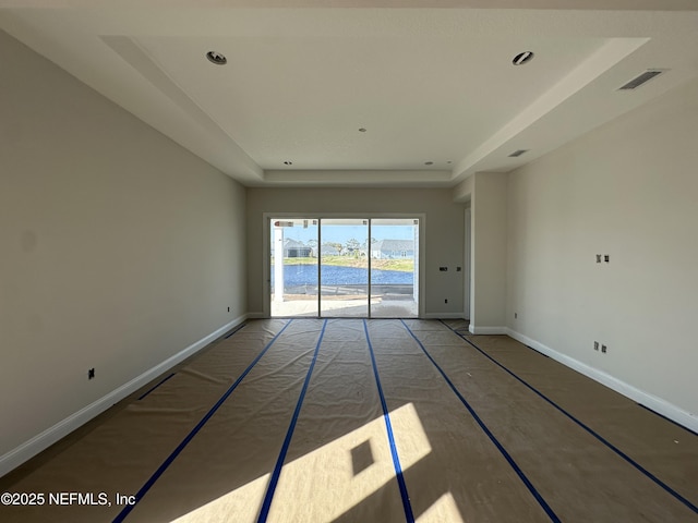 unfurnished room with recessed lighting, a raised ceiling, visible vents, and baseboards