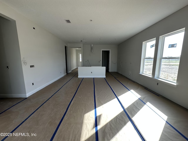 unfurnished living room featuring visible vents and a textured ceiling