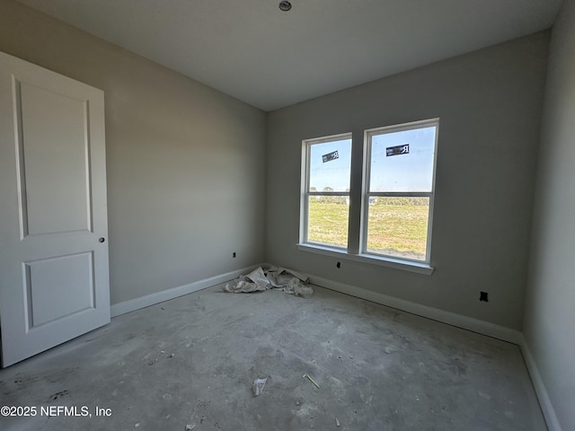 spare room with baseboards and unfinished concrete floors