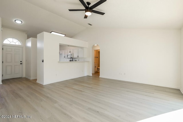 unfurnished living room with ceiling fan, light wood-type flooring, and vaulted ceiling