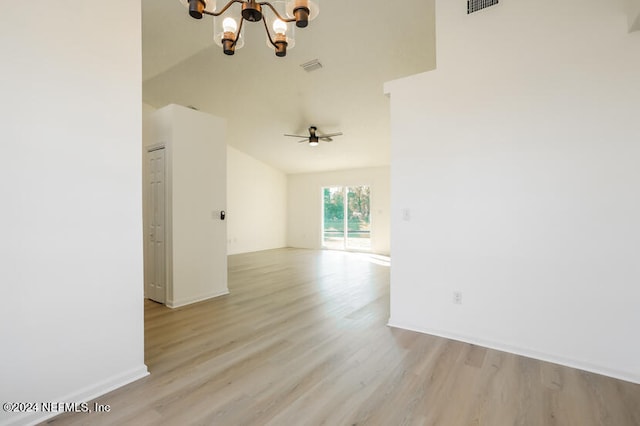 spare room featuring ceiling fan with notable chandelier, light wood-type flooring, and high vaulted ceiling