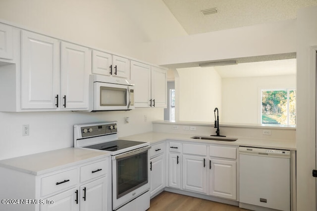 kitchen with light wood-type flooring, a textured ceiling, white appliances, sink, and white cabinetry