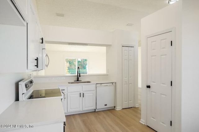 kitchen with dishwasher, stove, sink, light wood-type flooring, and white cabinetry