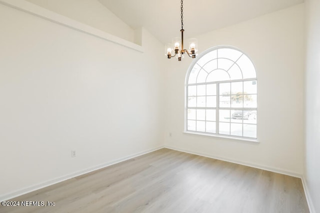 empty room with a chandelier, light hardwood / wood-style floors, and vaulted ceiling