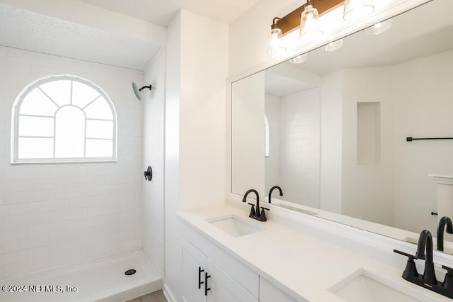 bathroom featuring a tile shower and vanity