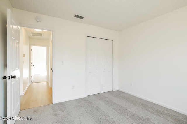 unfurnished bedroom featuring light colored carpet and a closet