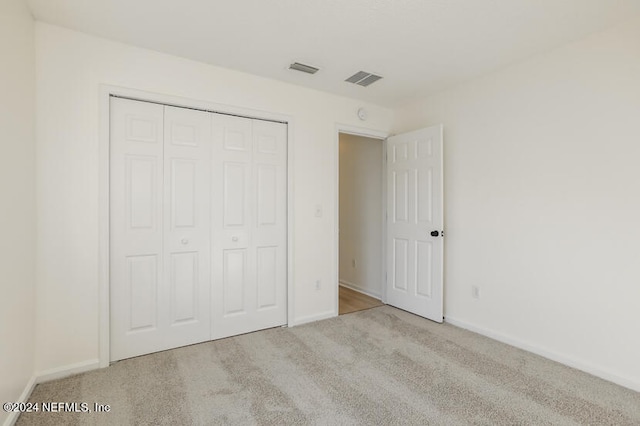 unfurnished bedroom featuring light carpet and a closet