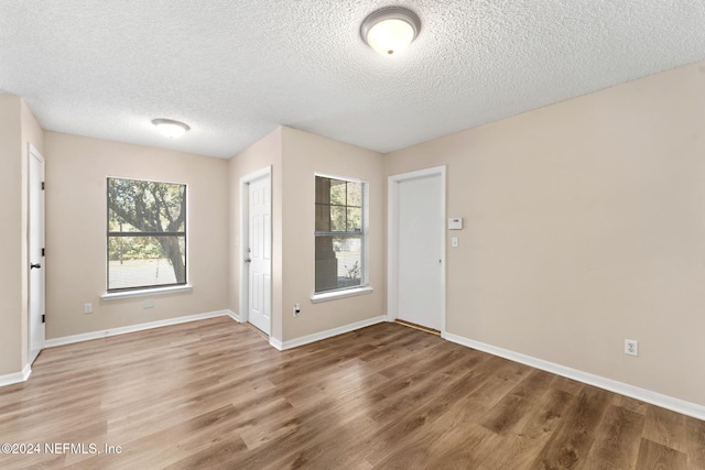 interior space with a wealth of natural light, a textured ceiling, and hardwood / wood-style flooring