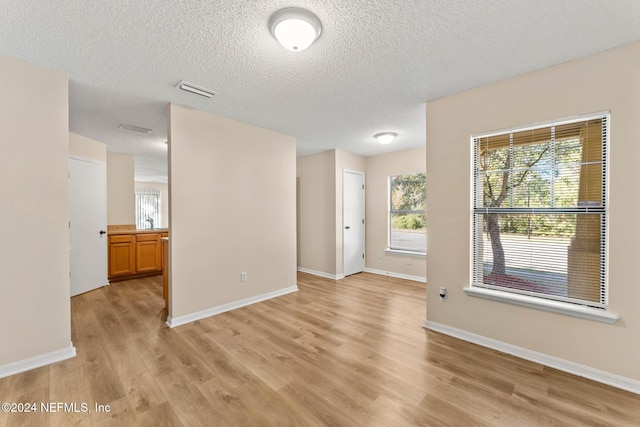 spare room featuring a textured ceiling and light hardwood / wood-style flooring