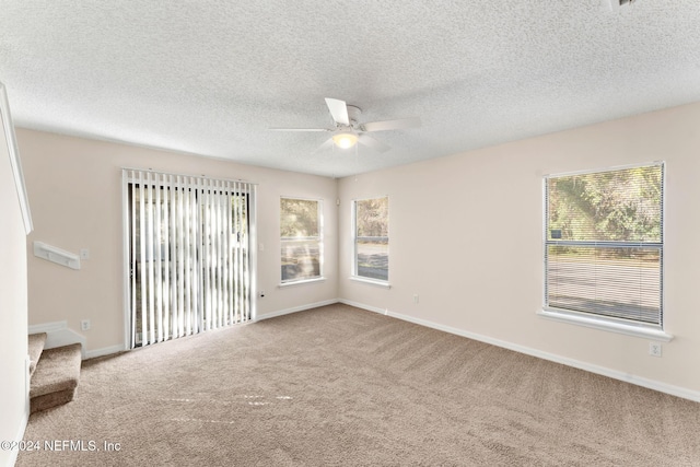 carpeted spare room featuring ceiling fan and a textured ceiling