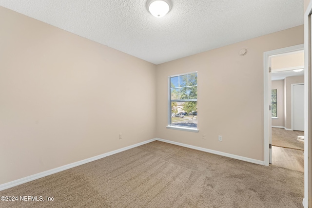 carpeted spare room with a textured ceiling