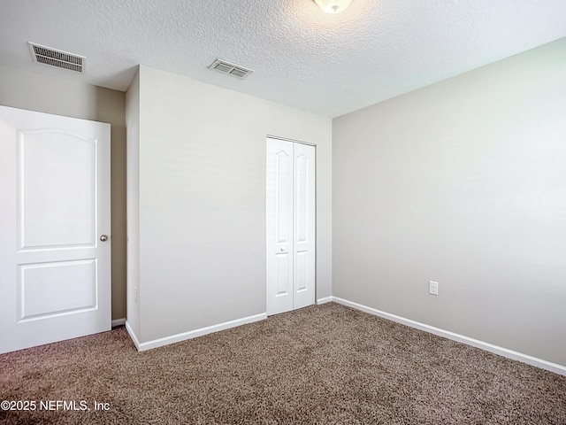 unfurnished bedroom featuring a textured ceiling, a closet, and carpet flooring