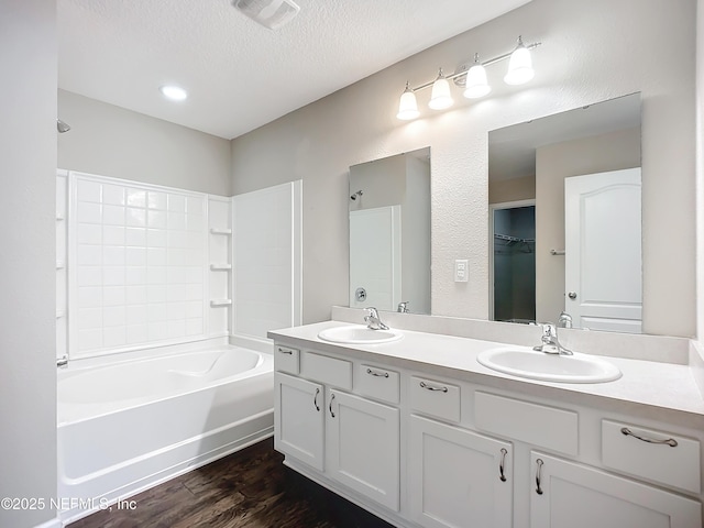 bathroom featuring a textured ceiling, shower / bathtub combination, hardwood / wood-style floors, and vanity