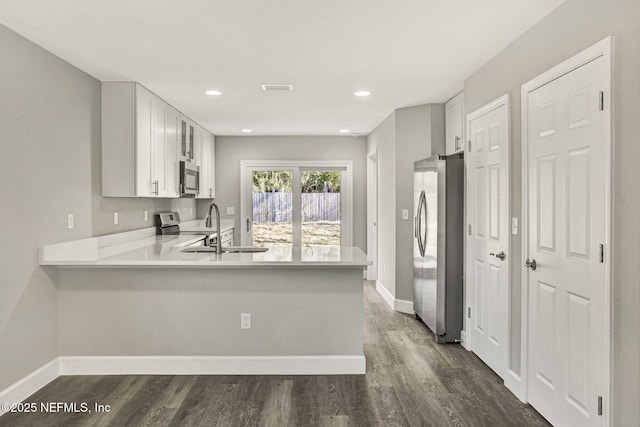 kitchen with white cabinetry, appliances with stainless steel finishes, sink, and kitchen peninsula