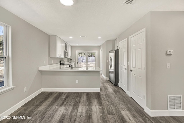 kitchen featuring stainless steel appliances, white cabinetry, a healthy amount of sunlight, and kitchen peninsula