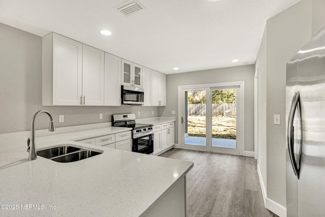 kitchen featuring light stone counters, sink, white cabinetry, and stainless steel appliances