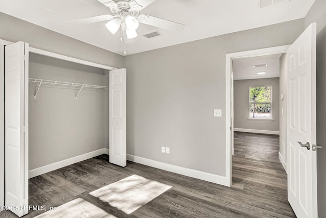 unfurnished bedroom with ceiling fan, dark hardwood / wood-style flooring, and a closet