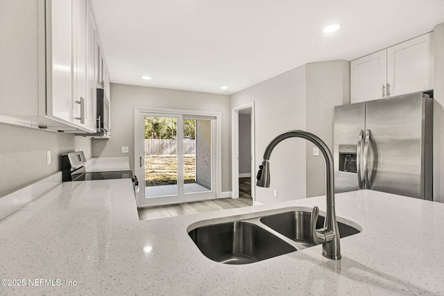 kitchen featuring sink, stainless steel appliances, white cabinets, and light stone countertops