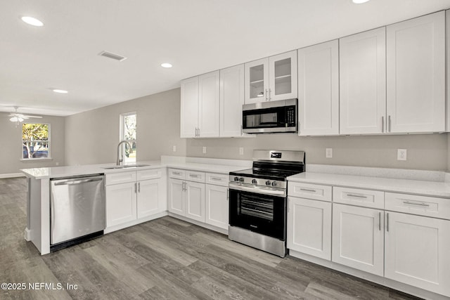 kitchen with stainless steel appliances, sink, white cabinets, and kitchen peninsula