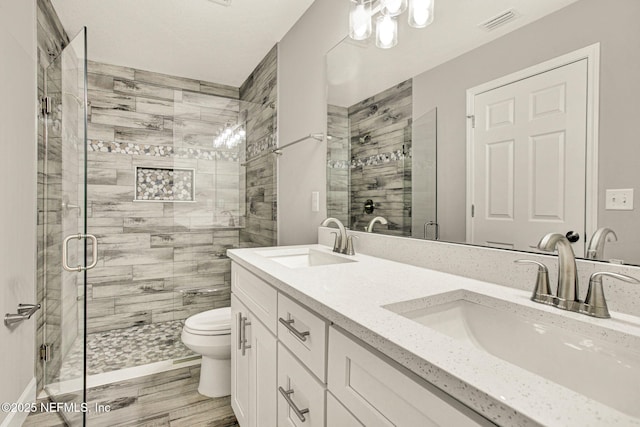 bathroom featuring a shower with door, vanity, hardwood / wood-style floors, and toilet