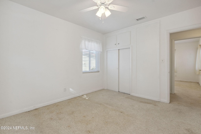 unfurnished bedroom with ceiling fan, a closet, and light carpet