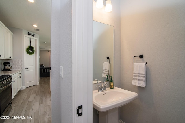 bathroom with tasteful backsplash, sink, and wood-type flooring