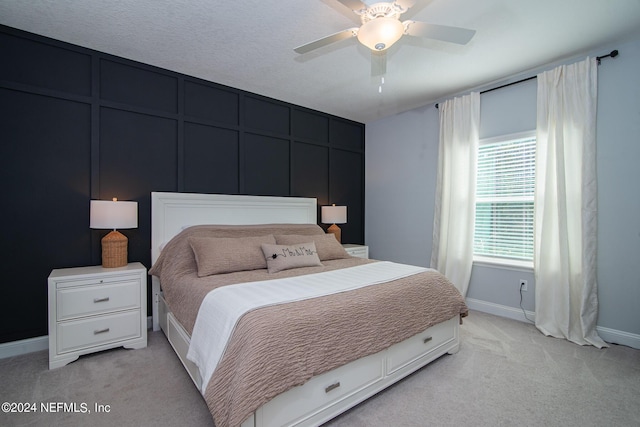 bedroom with ceiling fan, light carpet, and a textured ceiling