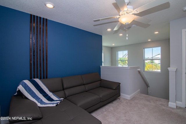 living room featuring a textured ceiling, ceiling fan, and light carpet