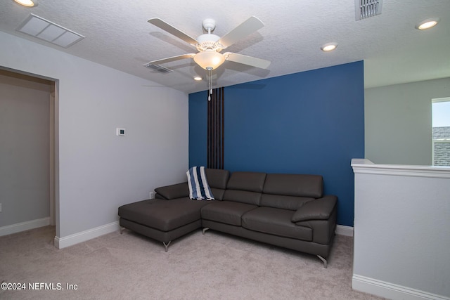 living room with ceiling fan, light colored carpet, and a textured ceiling