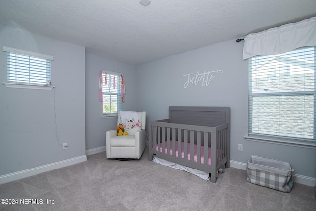 bedroom with carpet, a textured ceiling, and a nursery area