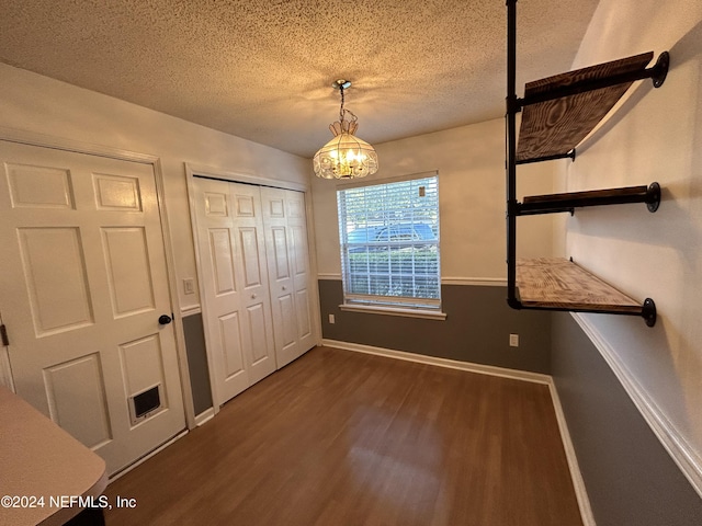 unfurnished bedroom with a closet, dark hardwood / wood-style flooring, a chandelier, and a textured ceiling