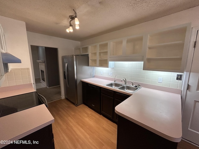 kitchen with tasteful backsplash, stainless steel fridge, sink, and light hardwood / wood-style floors