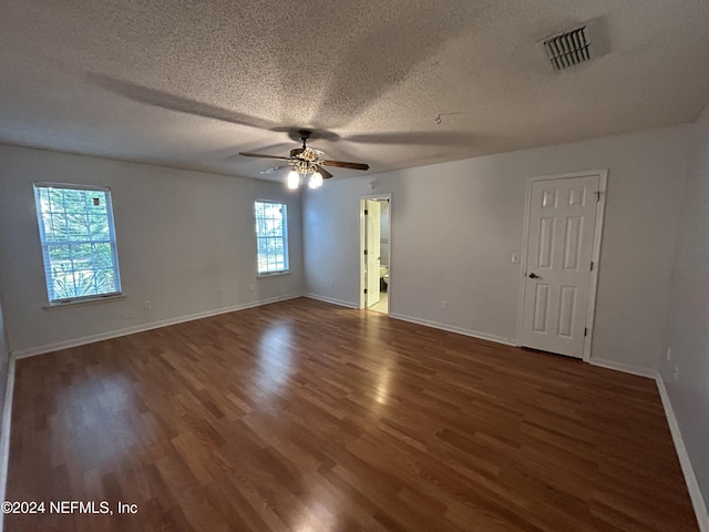 unfurnished room with a textured ceiling, a wealth of natural light, ceiling fan, and dark hardwood / wood-style floors