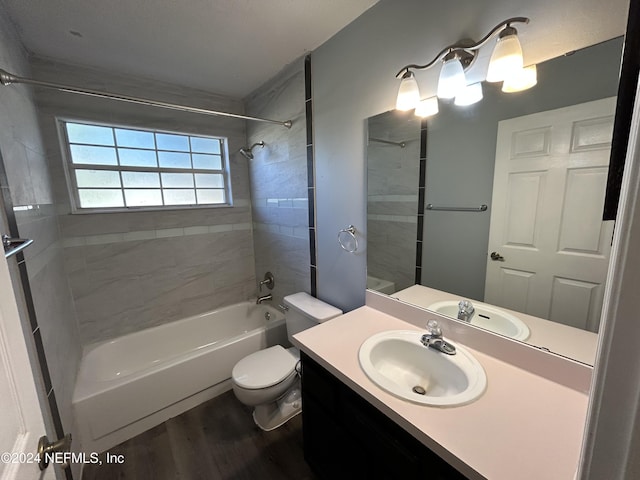 full bathroom featuring hardwood / wood-style floors, vanity, toilet, and tiled shower / bath