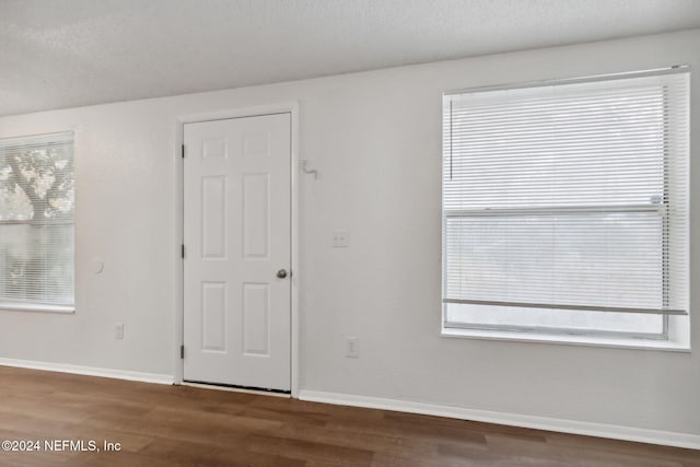 spare room featuring dark hardwood / wood-style floors and a textured ceiling