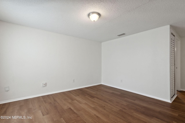 unfurnished room featuring dark hardwood / wood-style floors and a textured ceiling